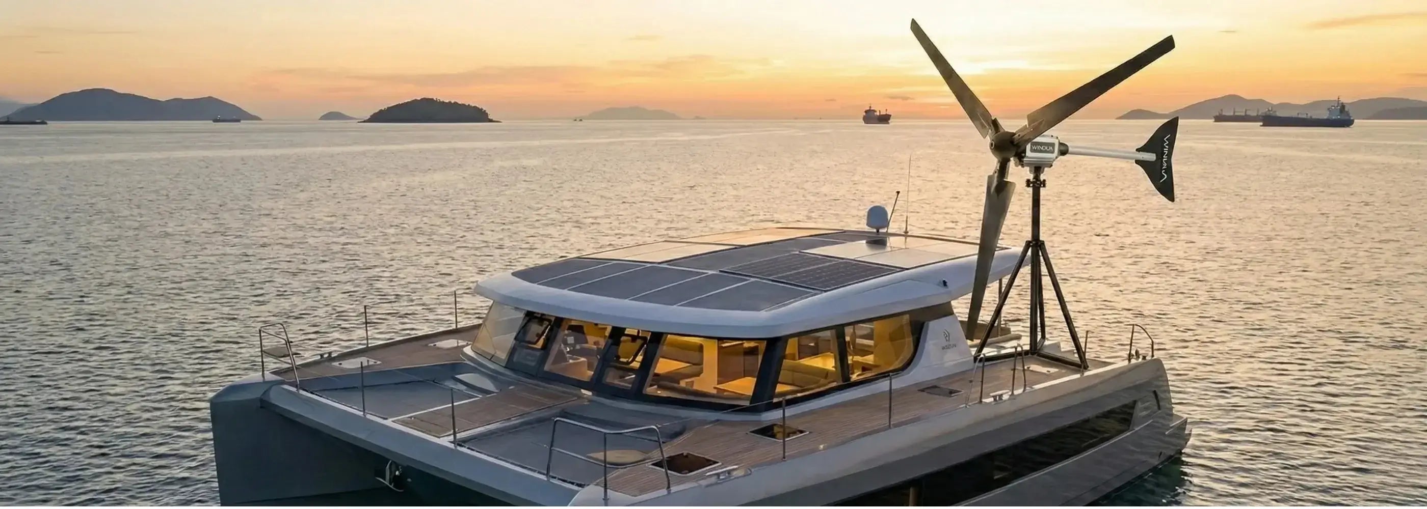 Techto Enerji Windua serisi sessiz rüzgar türbini ve güneş panelleri ile donatılmış, deniz üzerinde gün batımında hibrit enerji üreten modern katamaran tekne.